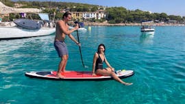 Pareja practicando paddle surf dentro de la excursión en barco al atardecer de MiniBar&Co en Mallorca