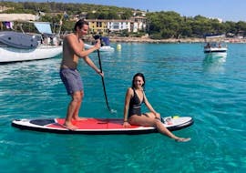 Pareja practicando paddle surf dentro de la excursión en barco al atardecer de MiniBar&Co en Mallorca