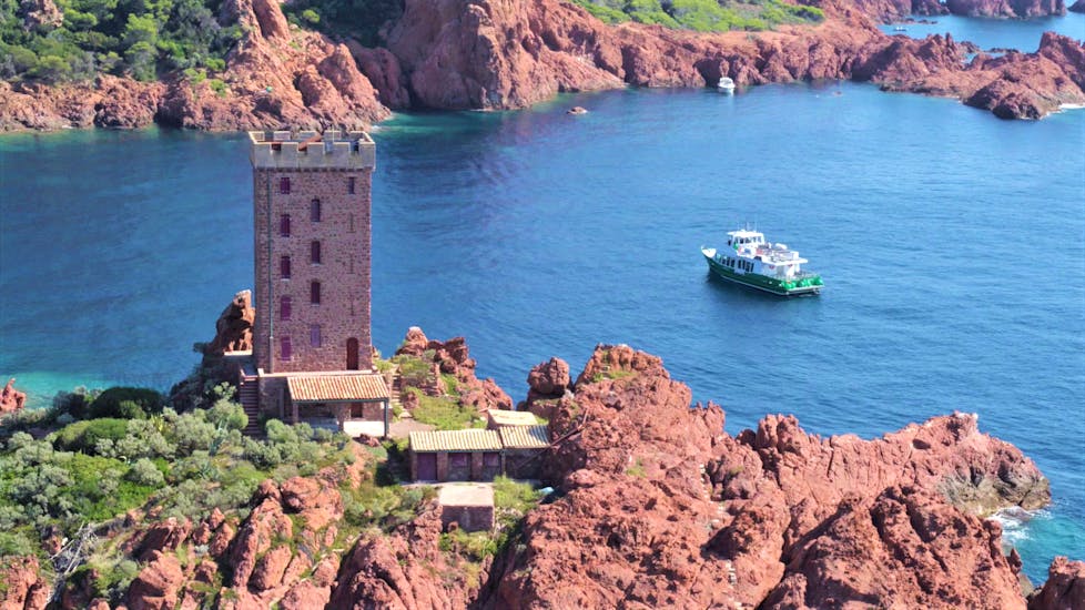 View of a tower and one of the Les Bateaux verts boat during their Boat tour to the Esterel Coves from Saint-Tropez.