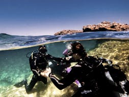 Een instructeur die iemand help onderwater tijdens de Discover Scuba Duiken voor beginners met ABC Diving Malta.