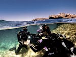 The instructor guiding someone underwater during the PADI Discover Scuba Diving Experience in St. Paul's Bay from ABC Diving Malta.