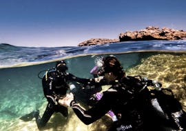 Een instructeur die iemand help onderwater tijdens de Discover Scuba Duiken voor beginners met ABC Diving Malta.
