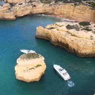 Two boats drive around a rock while doing a Private Boat Trip to Benagil Cave & Alfanzina Lighthouse with Snorkeling organized by EasyDream Charters Albufeira.