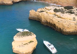 Two boats drive around a rock while doing a Private Boat Trip to Benagil Cave & Alfanzina Lighthouse with Snorkeling organized by EasyDream Charters Albufeira.