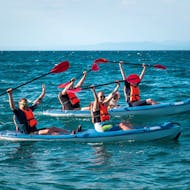 Menschen auf einem Kajak, eines mit einem Hund darauf, während ihrer Morgen-Kajaktour auf dem Meer ab Piran mit Sea Kayak Piran.
