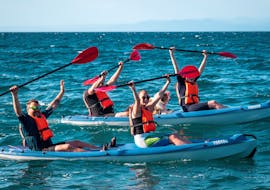 Menschen auf einem Kajak, eines mit einem Hund darauf, während ihrer Morgen-Kajaktour auf dem Meer ab Piran mit Sea Kayak Piran.