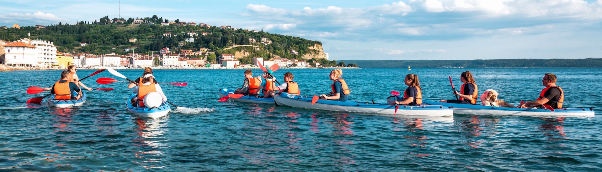Menschen paddeln in ihren Kajaks während ihrer Morgen-Kajaktour auf dem Meer ab Piran.