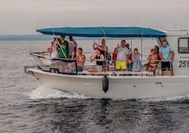 Menschen auf dem Boot während der Delfinbeobachtungs-Tour während dem Sonnenuntergang in Fažana mit Brijunu Panorama Istria.