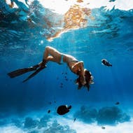Underwater image of a women from WeDive Lagos doing an underwater roll while snorkeling in the crystal clear ocean water in Lagos.