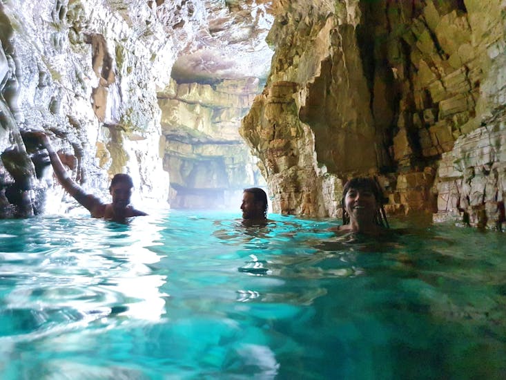 Three people enjoy the turquoise water in a cave while doing a Boat Trip from Fažana to the Seagulf Caves with Snorkeling.