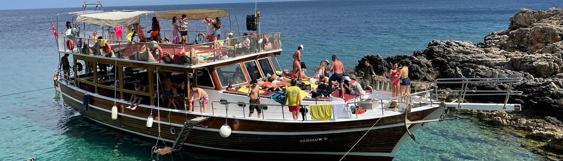 The boat filled with people and swimming next to it during one the stops of the Boat Tour in Bodrum with Swimming Stops from Yagmur D Bodrum.