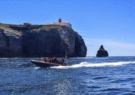 Een boot op het water met de Cabo de São Vicente op de achtergrond tijdens de Boottocht rond Cabo de S. Vicente met Cape Cruiser Sagres.