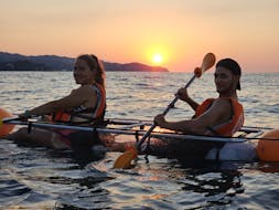 Beautiful orange Sunrise Sea Kayak Tour with transparent kayaks around Blanes coves from Crystal Kayaks & SUP Blanes.