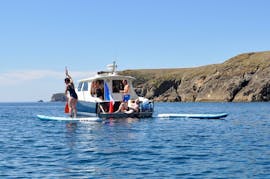 Un grupo de personas en un bote con tablas de paddle durante el tour privado en barco a la isla de Groix con almuerzo.
