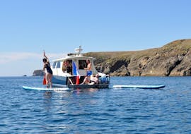 Un grupo de personas en un bote con tablas de paddle durante el tour privado en barco a la isla de Groix con almuerzo.