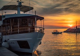 A boat sails on the ocean while the sun is setting during the Sunset Boat Trip to Brijuni National Park with Dinner & Dolphin Watching organized by Excursions Ulika Pula - Alfio.