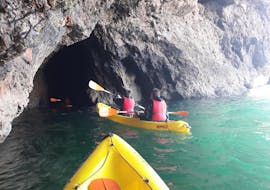 Twee mensen die een grot in kajakken tijdens de Kajaktocht in Salema door grotten met Salema Tours.