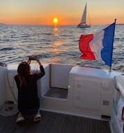 Bild einer Frau, die während eines privaten Sonnenuntergangsbootsausflugs von Locmiquélic mit Abendessen an Bord einen Sonnenuntergang fotografiert.
