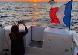 Afbeelding van een vrouw die een foto maakt van de zonsondergang tijdens een privé-zonsondergangboottocht vanuit Locmiquélic met diner aan boord.