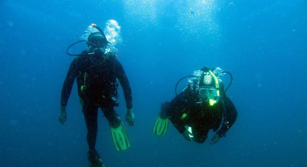 Unterwasseraufnahme von zwei Tauchern, die im klaren blauen Wasser in Albufeira ein Schnuppertauchen mit Indigo Divers Albufeira machen.