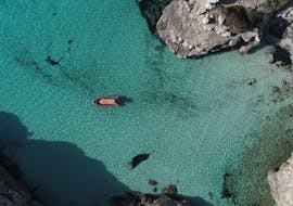 Boat Trip to Caló des Moro y s'Almunia from Cala Figuera - Nature Tour: serene scene of a boat anchored in turquoise waters surrounded by rugged cliffs and lush greenery.