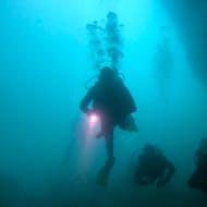 Unterwasseraufnahme eines Tauchers mit einer Taschenlampe in einer Höhle, beim Advanced Open Water Diver Tauchkurs in Albufeira mit Indigo Divers Albufeira.