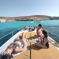 People on the boat from Boat Trip in Comino to the Blue Lagoon with Swimming from Mitzi Tours Malta relaxing and enjoying their snacks.
