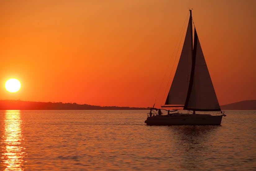 Ein Boot segelt in den Sonnenuntergang während der Sonnenuntergangs-Bootstour nach Stalis & Hersonisos mit Abendessen und Badestopps organisiert von Malia Yachting.