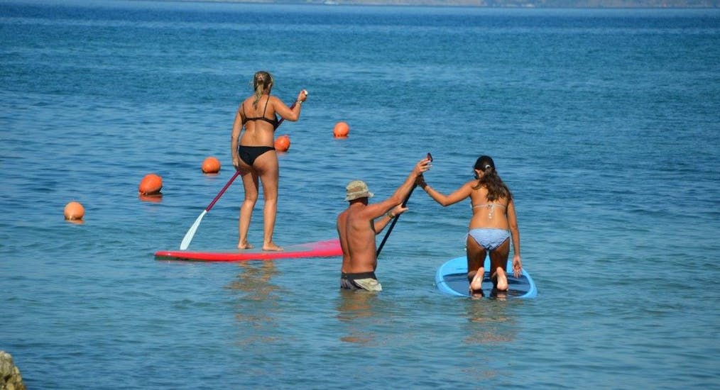 The instructor helping the people with their SUPs at the start of their SUP Rental at the Alykes Potamos Beach in Corfu with Corfu Surf Club.