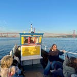 Un grupo de participantes en el barco, con el Puente 25 de Abril al fondo, durante el paseo en barco por el río Tajo a lo largo de la costa de Lisboa con música de fado de Lisbon Boats.