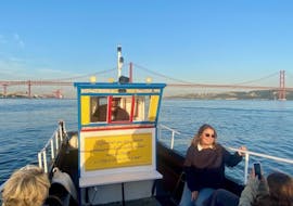 Eine Gruppe von Teilnehmern auf dem Boot, mit der Ponte 25 de Abril im Hintergrund, während der Bootstour auf dem Tejo entlang der Küste von Lissabon mit Fado-Musik von Lisbon Boats.