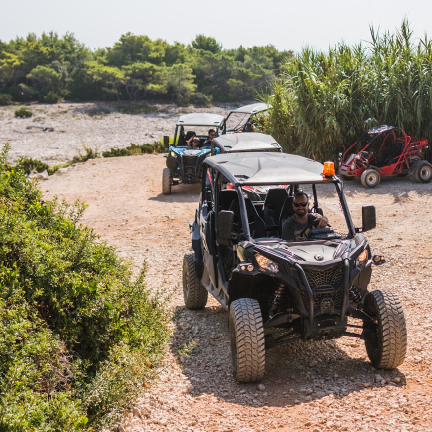 Horizontal image of a guy driving a buggy during a buggy safari in Korčula with local culinary tasting from Korkyra Info Korčula.