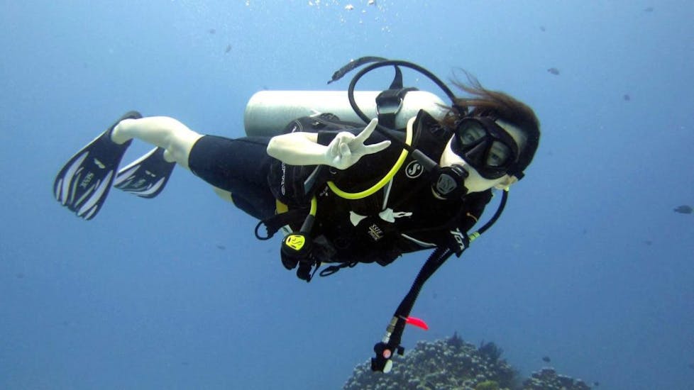A girl doing the peace sign underwater during the Trial Dive in Naxos for Beginners from Blue Fin divers.