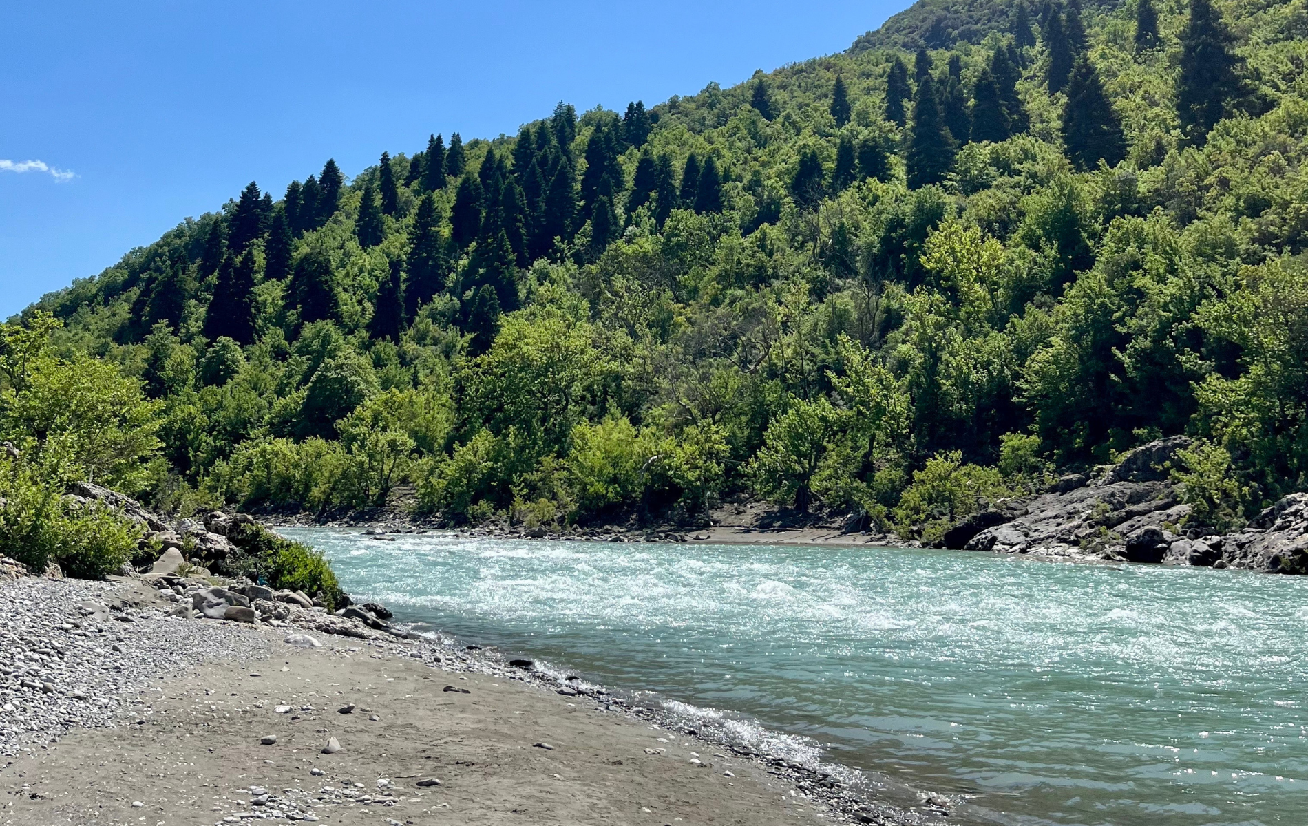 Der wunderschöne blaue Fluss Vjosa mit Leuten im Boot beim Rafting am Vjosa Wildfluss in Gjirokaster mit Vjosa Explorer Rafting Albania.