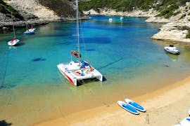 A boat is anchored near a beach during the Catamaran Trip to the Lavezzi Islands with Swimming from Voiles de Bonifacio.