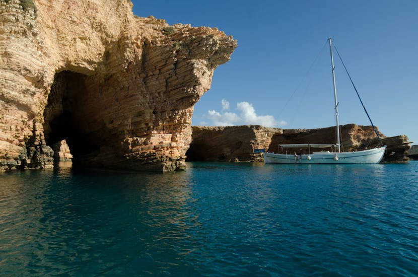 Le bateau qui est utilisé avec les magnifiques foramtions rocheuses et les falaises en arrière-plan pendant l'excursion privée en voilier à Koufonisia et Naxos avec plongée en apnée avec le capitaine Yannis Cruises Kaiki Paros.