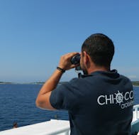 A member of the Choicca Croisières crew looks out at the ocean through binoculars during the Boat Trip from Porto-Vecchio to Lavezzi Islands.