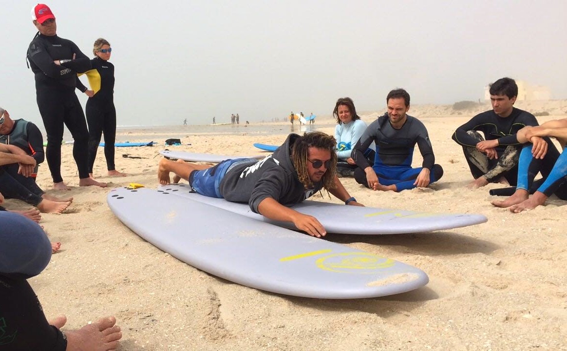 An instructor shows the correct posture on the board on the beach during Surf Lessons on Essaouira Beach (from 14 y.) from KiteTripping Kitesurf & Surf School Essaouira.