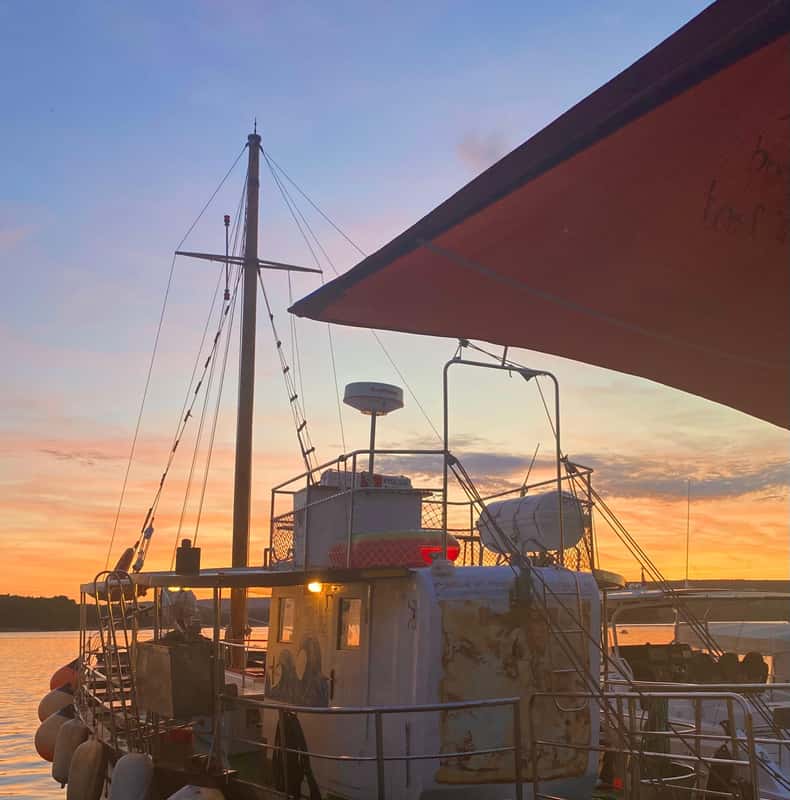 The M/B Kosljun Punat pirate ship is ready for an all-inclusive tour to discover Island Plavnik, shown here docked in the calm water as the sun sets.