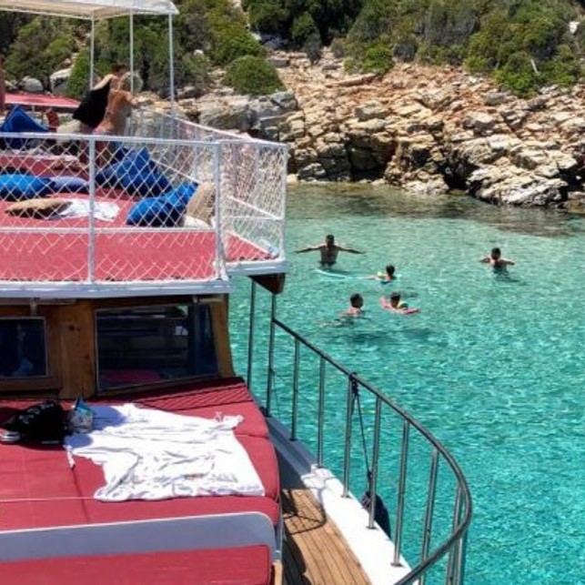 Das Boot mit Menschen, die im kristallklaren Wasser schwimmen, während der Bootstour zur Schwarzen Insel mit Mittagessen und Schwimmen mit Morning Travel Bodrum.