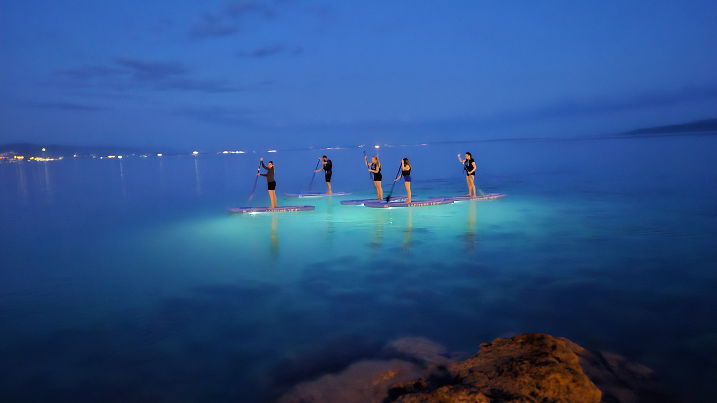 Group of friends enjoying a Stand Up Paddle Boarding Night Tour along Opatija from Opatija Adventure.