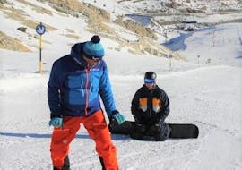 Un moniteur de snowboard enseigne quelques figures à un participant de cours particuliers de snowboard pour adultes organisées par l'école de ski Ski- und Snowboardschule SNOWLINES à Sölden.