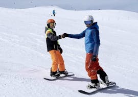 Een snowboardinstructeur heeft plezier op een piste met een jonge snowboarder tijdens Privé Snowboardlessen voor Kinderen georganiseerd door de skischool Ski- und Snowboardschule SNOWLINES Sölden in het skiresort van Sölden.