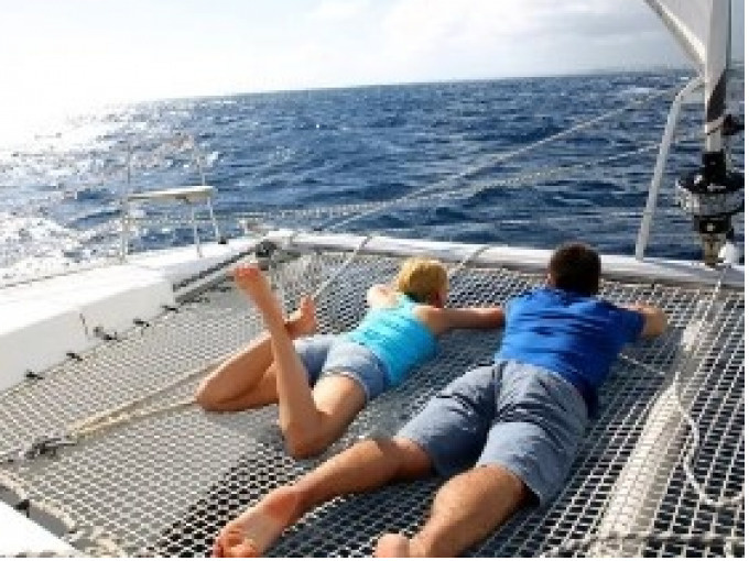 Two people in the catamaran's nets during the Full Day Catamaran Trip to the Robert Islets with Lunch & Swimming from Access Evasion Martinique.