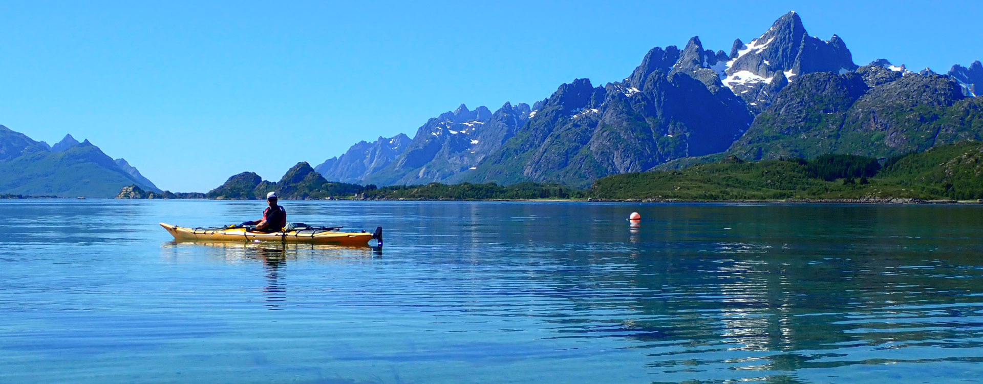 A participant of the Lofoten Aktiv kayak tour paddling in the sea with breathtaking views.