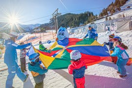 A group of small children is playing during their kids ski lessons "miniclub" with skischule Bad Hofstein.