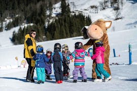 Eine Gruppe Kinder und ein Bärenmaskottchen während dem Kinder-Skikurs "Zwerge" (3-4 J.) mit Schi- & Snowboardschule Florian Kleinarl.