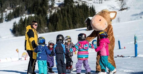 Kids Ski Lessons "Bambini" (3-4 y.) from Ski- & Snowboard School Florian Kleinarl A group of kids and a bear mascot during the Kids Ski Lessons "Bambini" (3-4 y.) from Ski- & Snowboard School Florian Kleinarl.