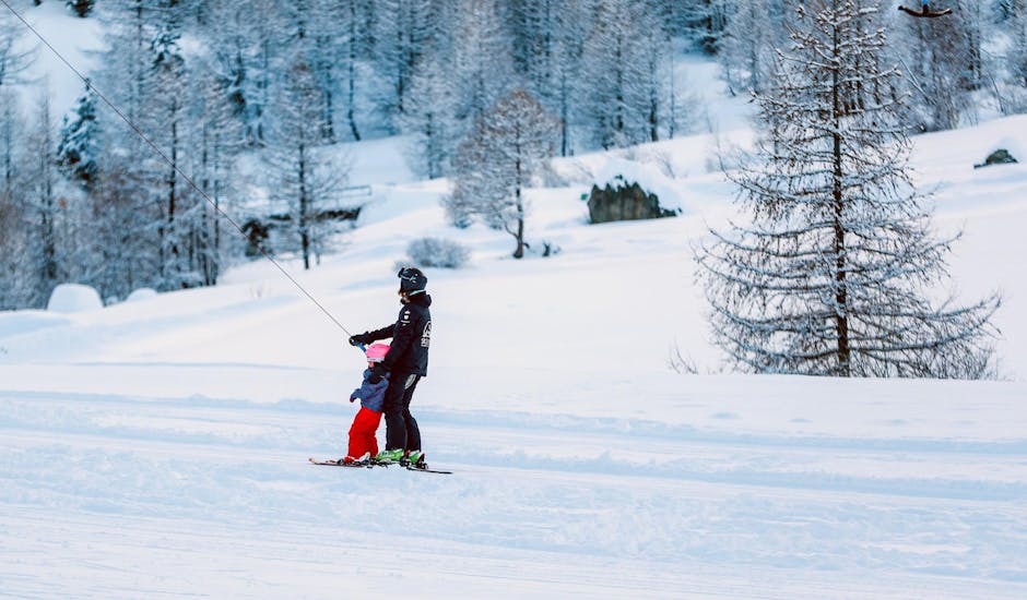 Een klein kind leert hoe hij de t-bar lift moet nemen tijdens privé skilessen voor kinderen voor beginners bij Skischool Zenit.