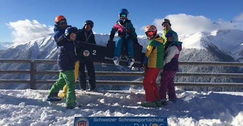 Cours de ski Enfants (8-14 ans) pour Skieurs avancés avec École Suisse de Ski de Davos Un groupe de skieurs tient un skieur pendant les cours de ski pour enfants "Parsenn" (10-14 ans) pour les skieurs avancés avec l'école de ski suisse de Davos.